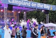 A grassy field with people on it in fromt of a stage at Campland On The Bay