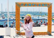 Girl on bike eating ice cream at the beach with a Campland sign.