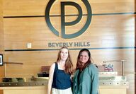 Women standing in front of Ocean Prime logo sign in restaurant in Beverly Hills